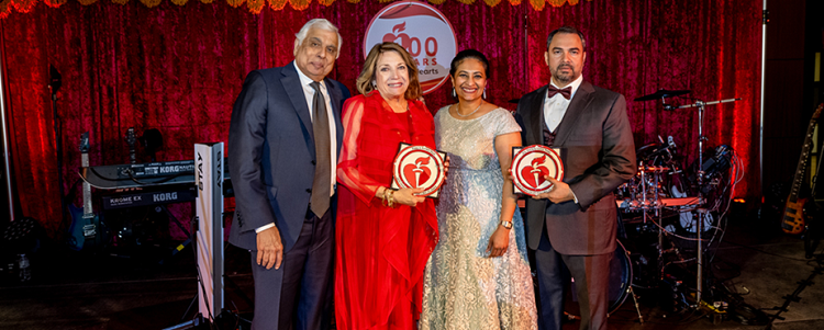 Four people standing on stage holding heart and torch awards